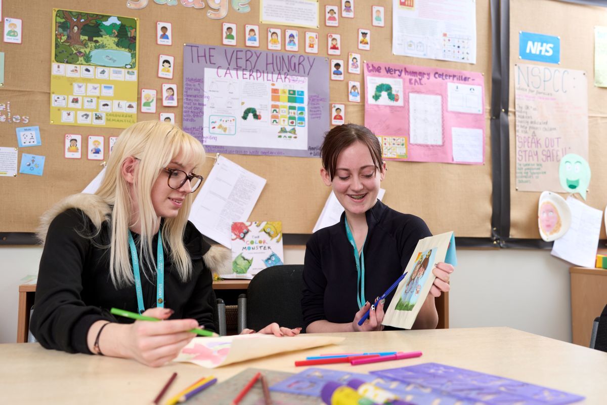 2 early years students showing off their work