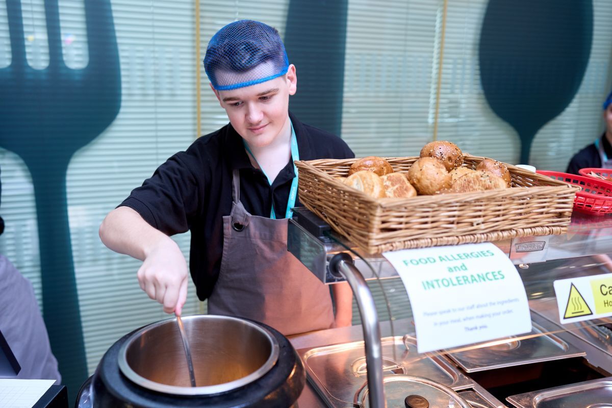 A catering student serving soup