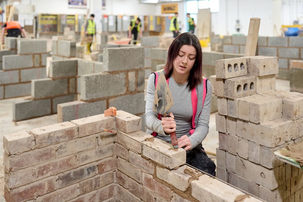 A female bricklaying student laying a brick