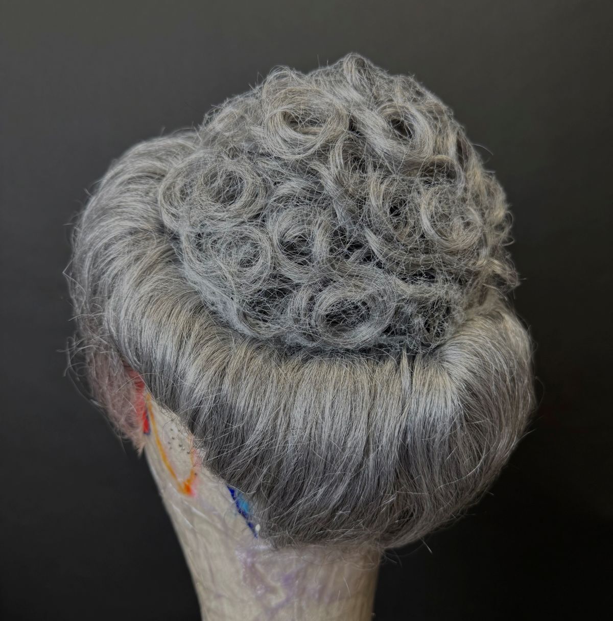 A grey wig on a dummy head modelled from the back