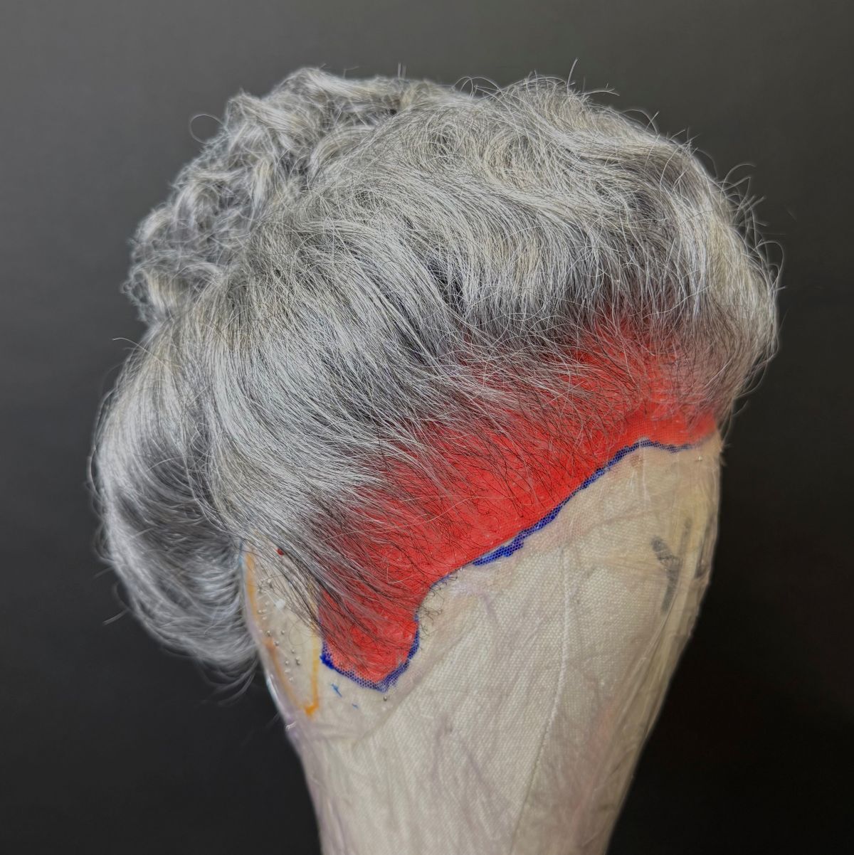 A grey wig on a dummy head modelled from the front