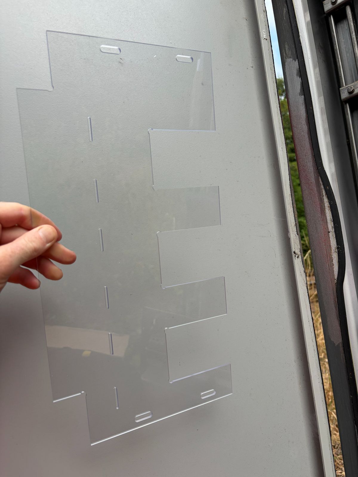 A hand holds the polycarbonate screen that Jackson Hall produced to stop rats getting in Network Rail signal boxes
