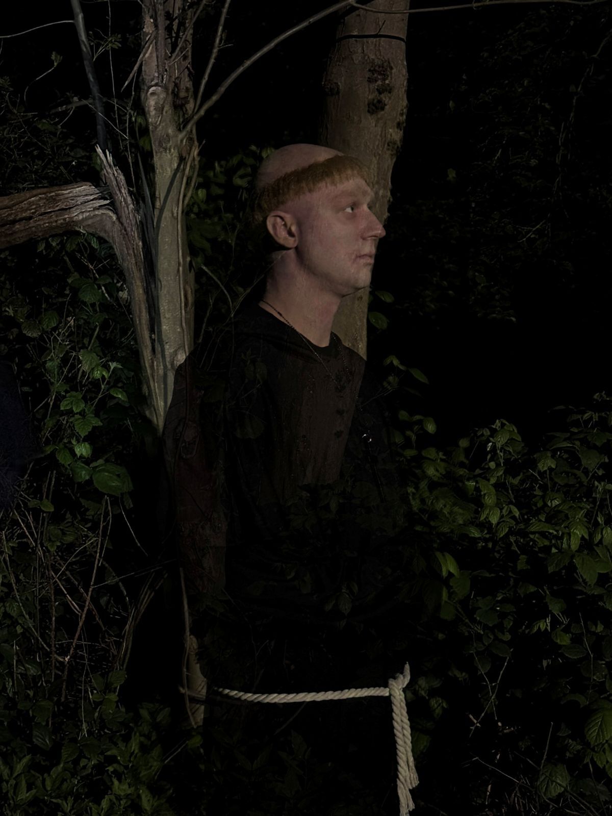 A monk stood in front of a tree in the dark in a scene from an untold ghost story
