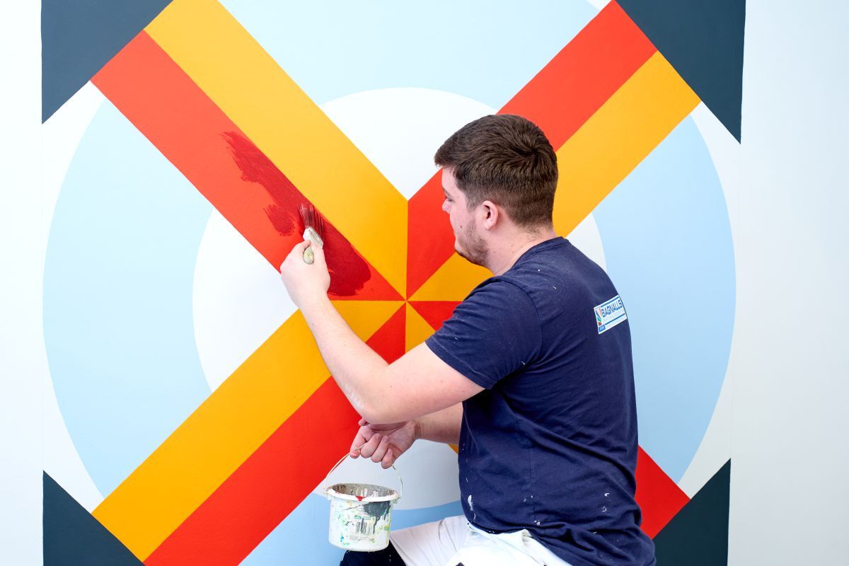 A painting decorating student painting a wall