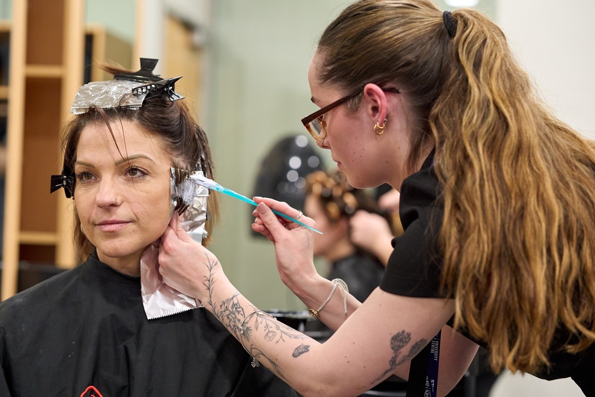 A student colours a clients hair Hairdressing