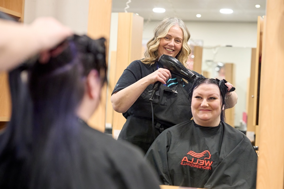 A student dries a clients hair Hairdressing