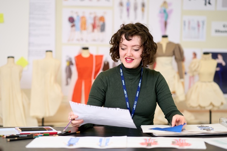 A student holds some work up to examine Fashion