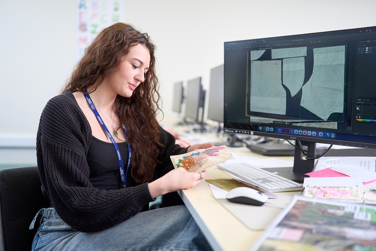 A student looks at some fabric and designs on a computer screen Fashion