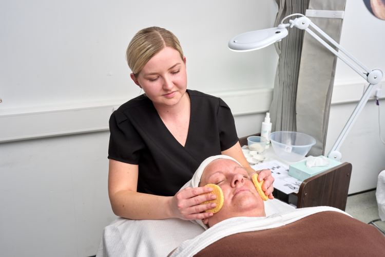 A student performs a facial on a client