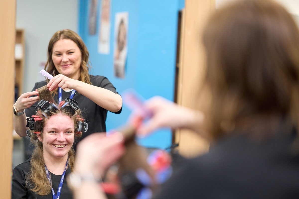A student puts a clients hair in rollers Hairdressing