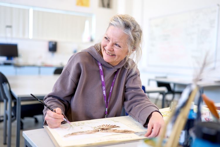 A student smiles as she paints