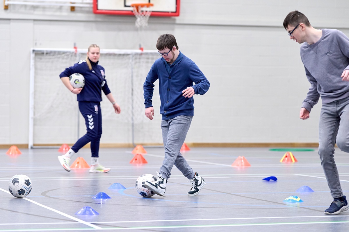 A vocational sports coaching student is running some football skills sessions in the sports hall