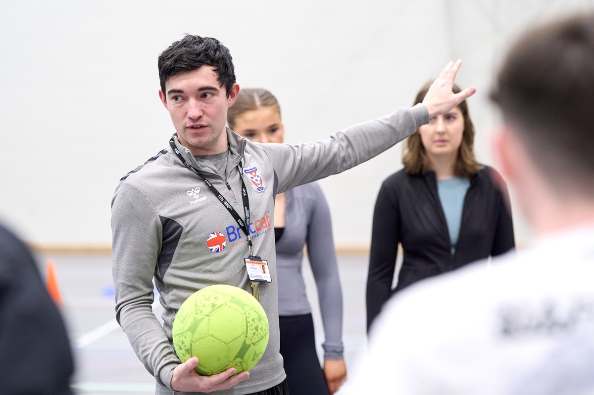 A vocational sports tutor is taking a coaching class in the sports hall