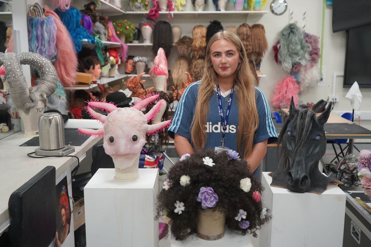 Abi Horton stood behind her media make up work on plinths including an axolotl a wig and a horses head