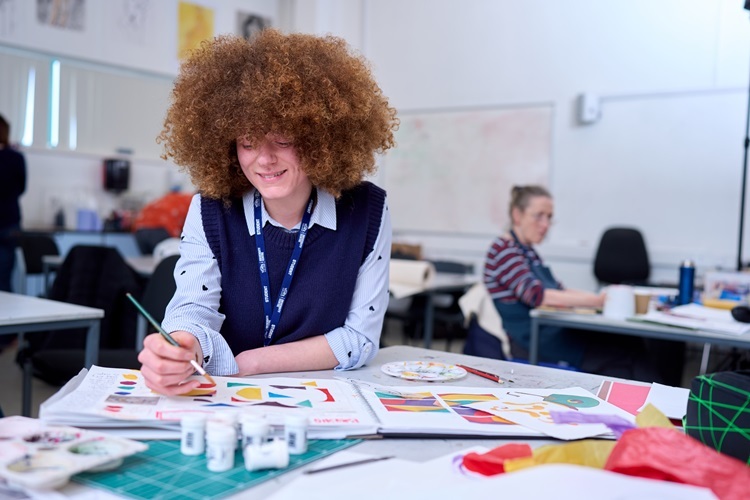 Access Art a student paints and smiles
