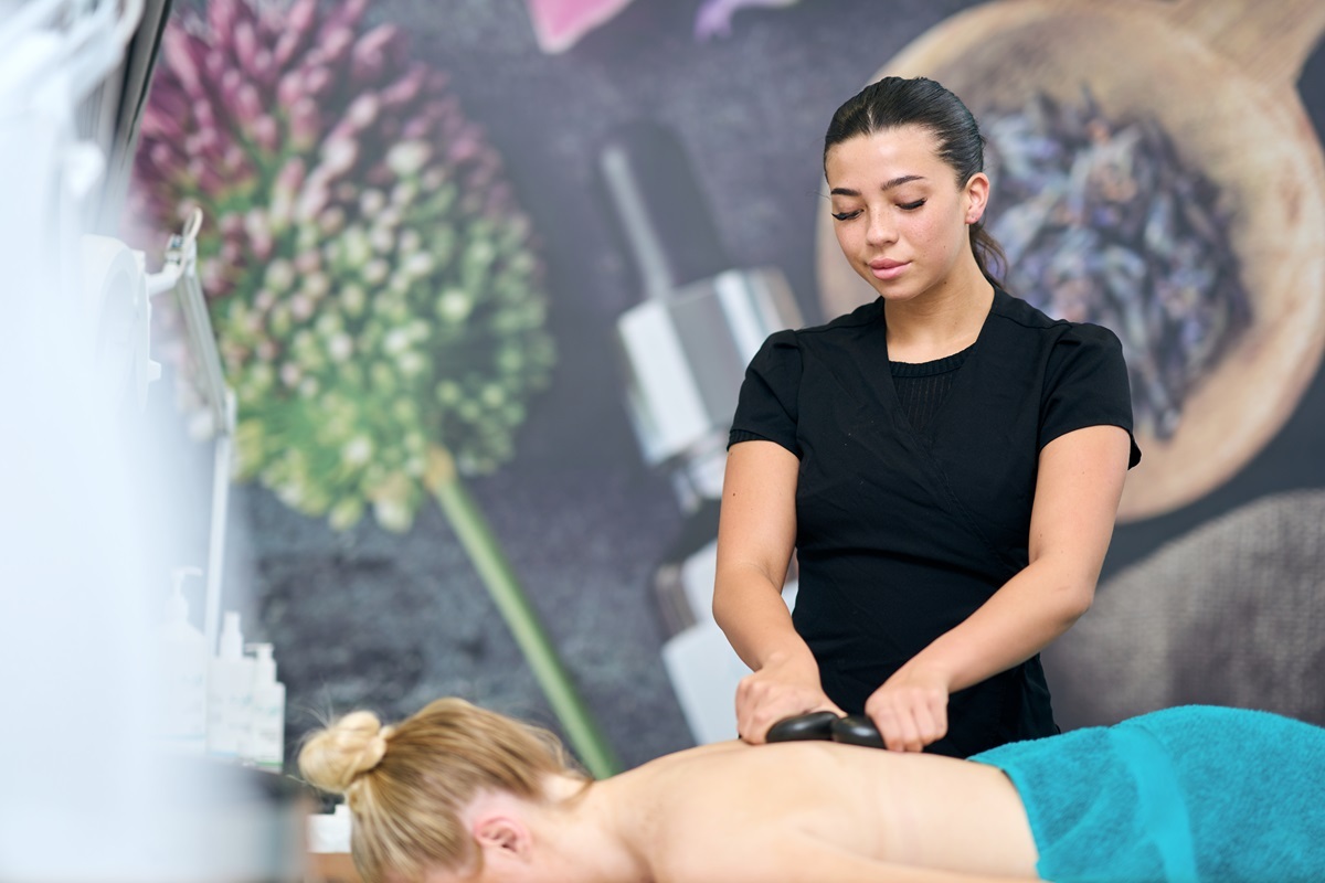 Beauty student providing a hot stone massage for a client