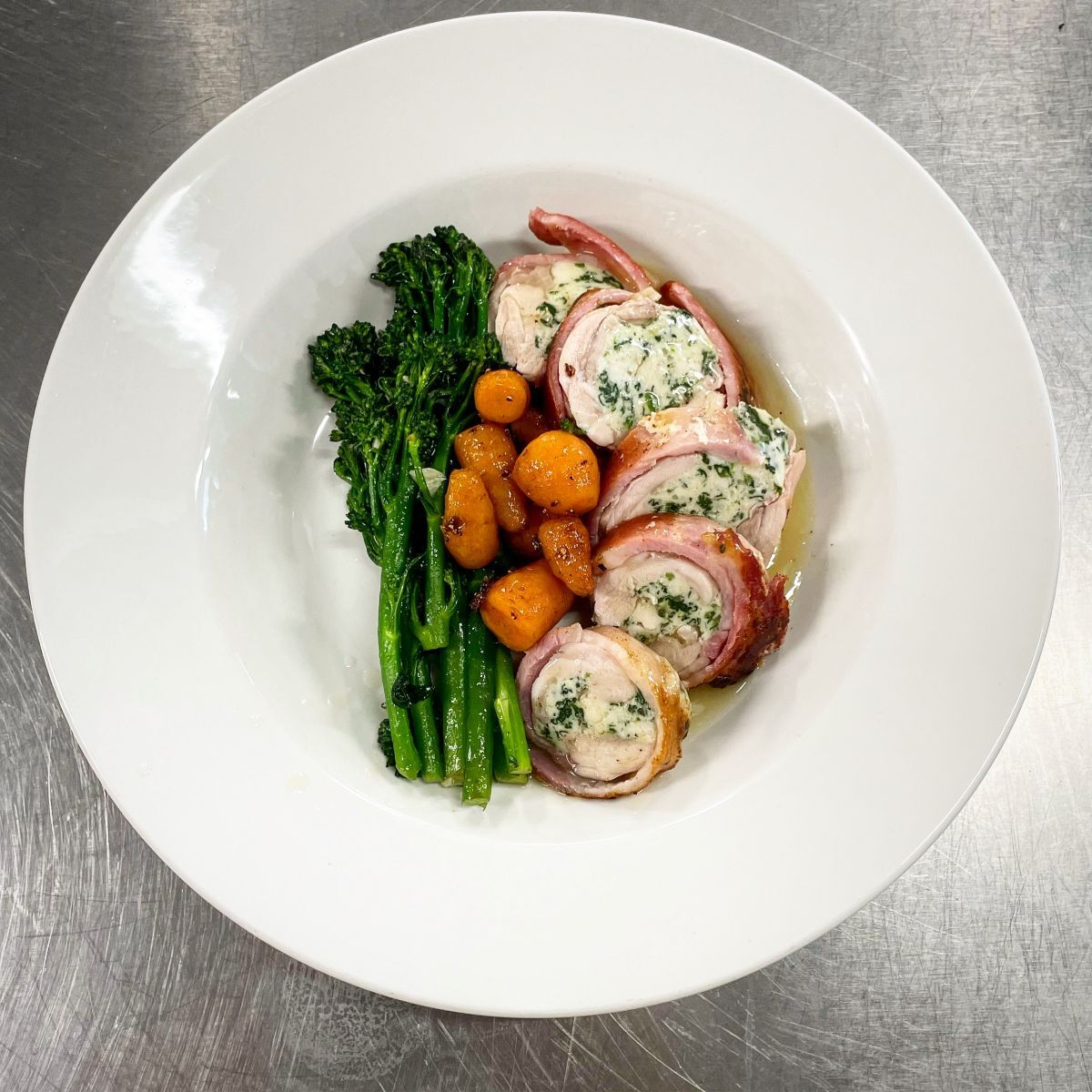 Chicken stuffed with cheese and wrapped in bacon with baby carrots and tenderstem broccoli