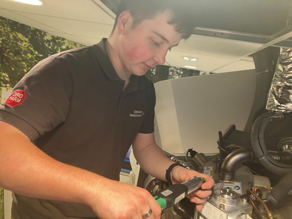 Close up of apprentice Sam Welch working on machinery in his Siemens Healthineers T shirt