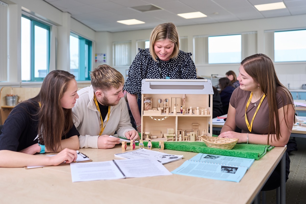 Early Years students looking at a dolls house