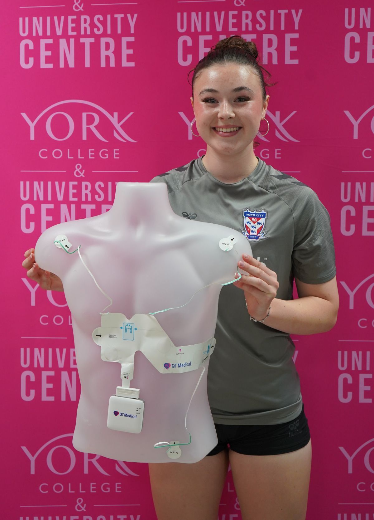 Footballer Megan Atkins holds up a torso dummy with electrode patches on it as part of the ECG testing kit