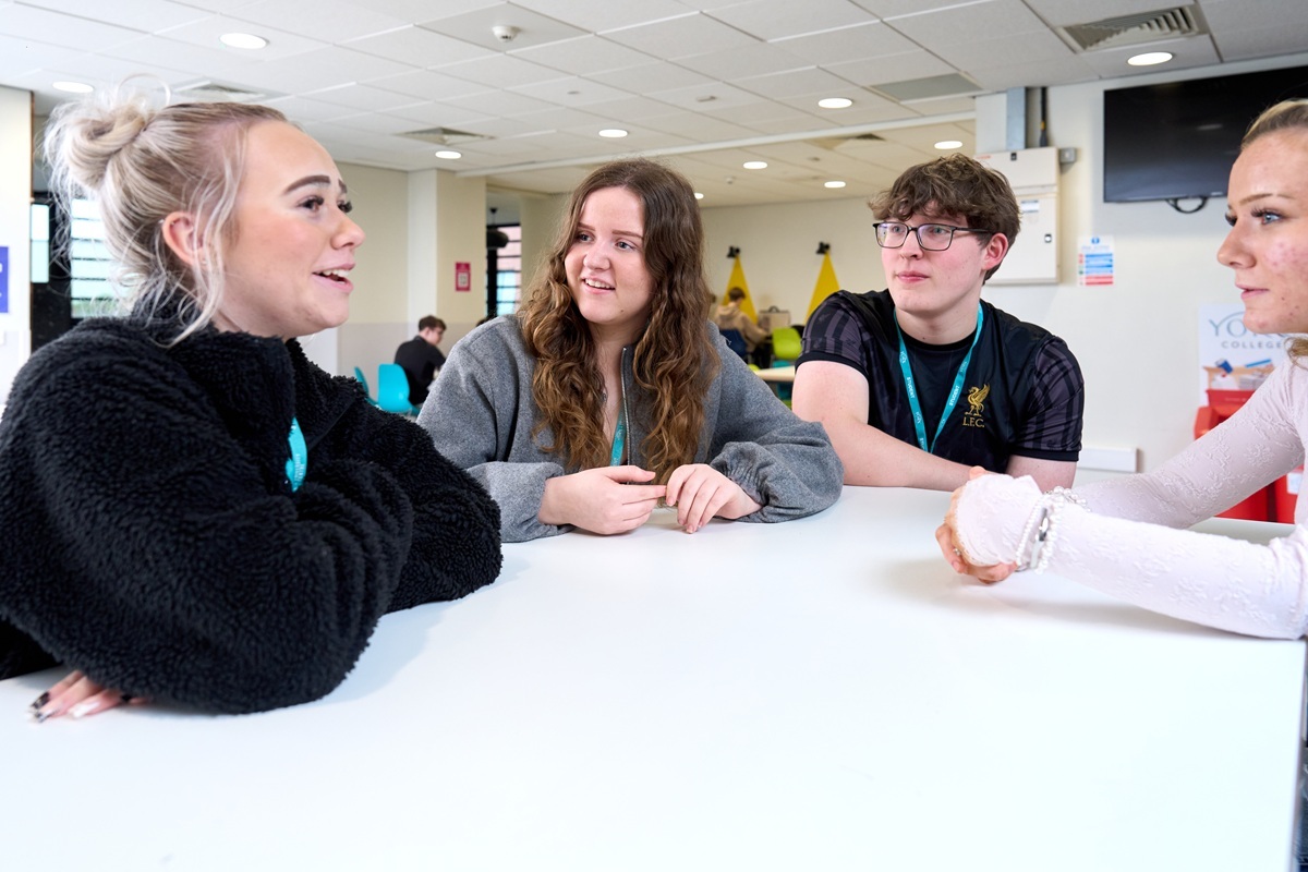 Four students sat around a high table in the social area talking