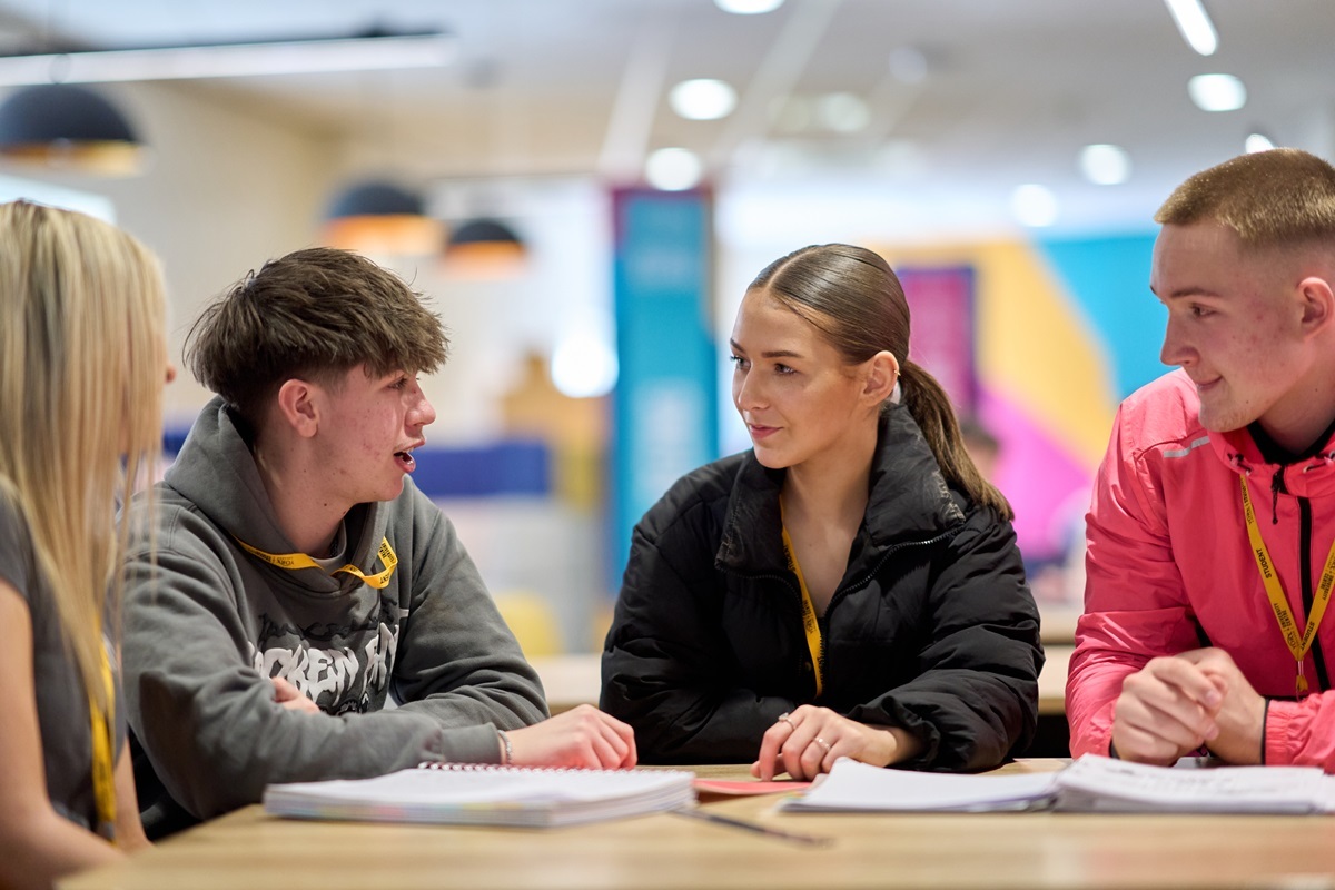 Four students sat around a table with notepads talking