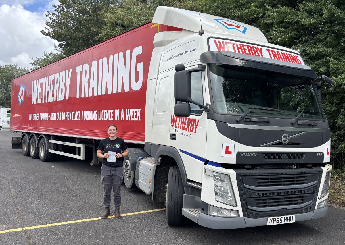 Georgina Richardson holds her HGV driving licence in front of a Wetherby Training lorry