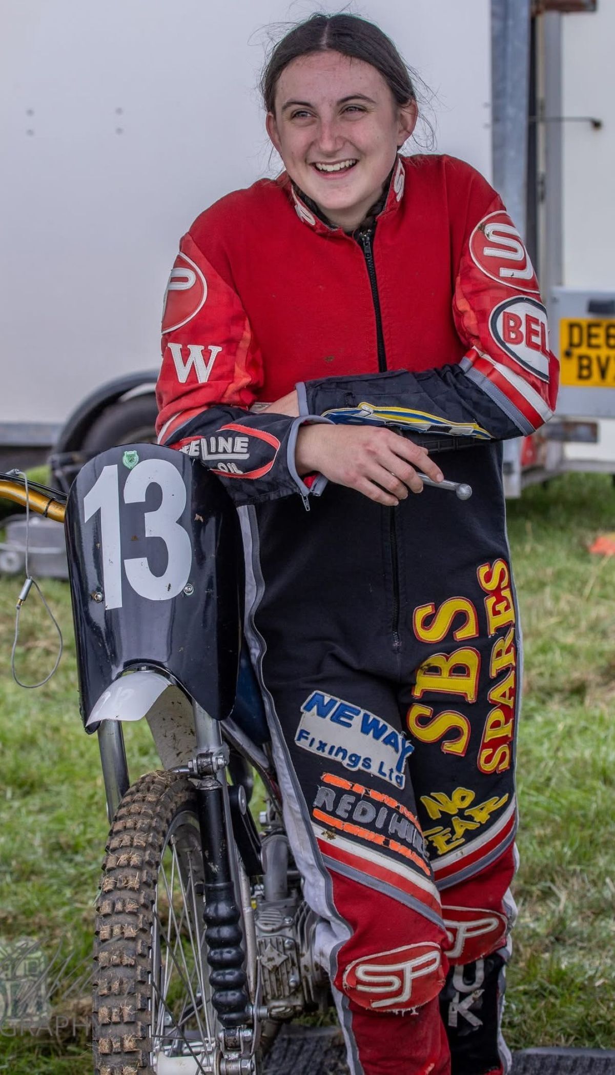 Georgina Richardson smiling and leaning on her motorbike in race outfit