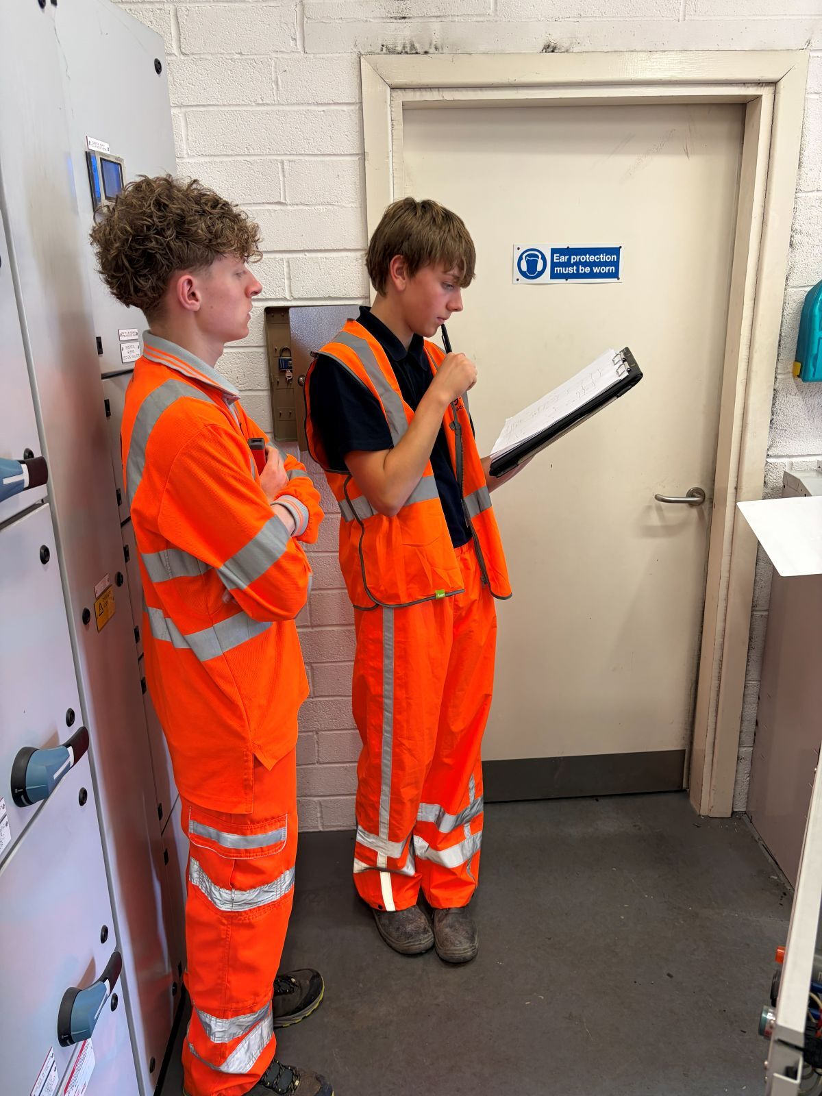 Jackson Hall in high vis top and bottoms studies a clipboard with a fellow AGH Engineering colleague