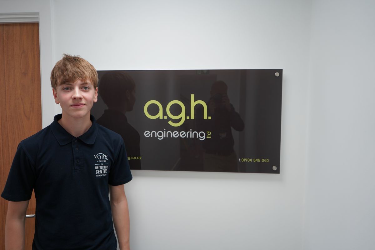 Jackson Hall stands in front of AGH Branding in the company office