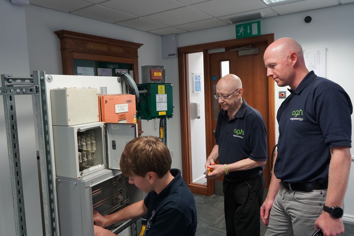 Jackson Hall works on the electrical training unit in AGH Engineerings office with Andy Windass and Adam Wood watching on