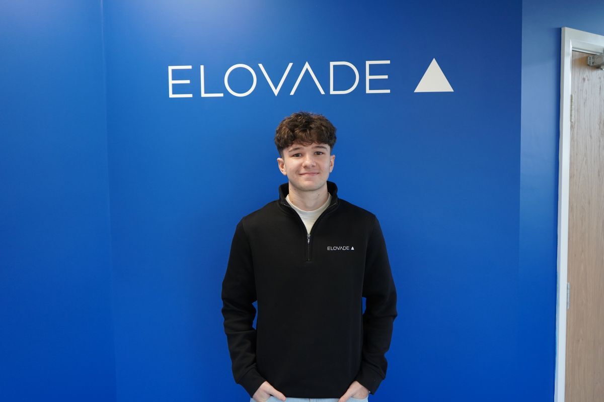 Josh Jenkins stood in front of a blue wall in front of Elovade branding