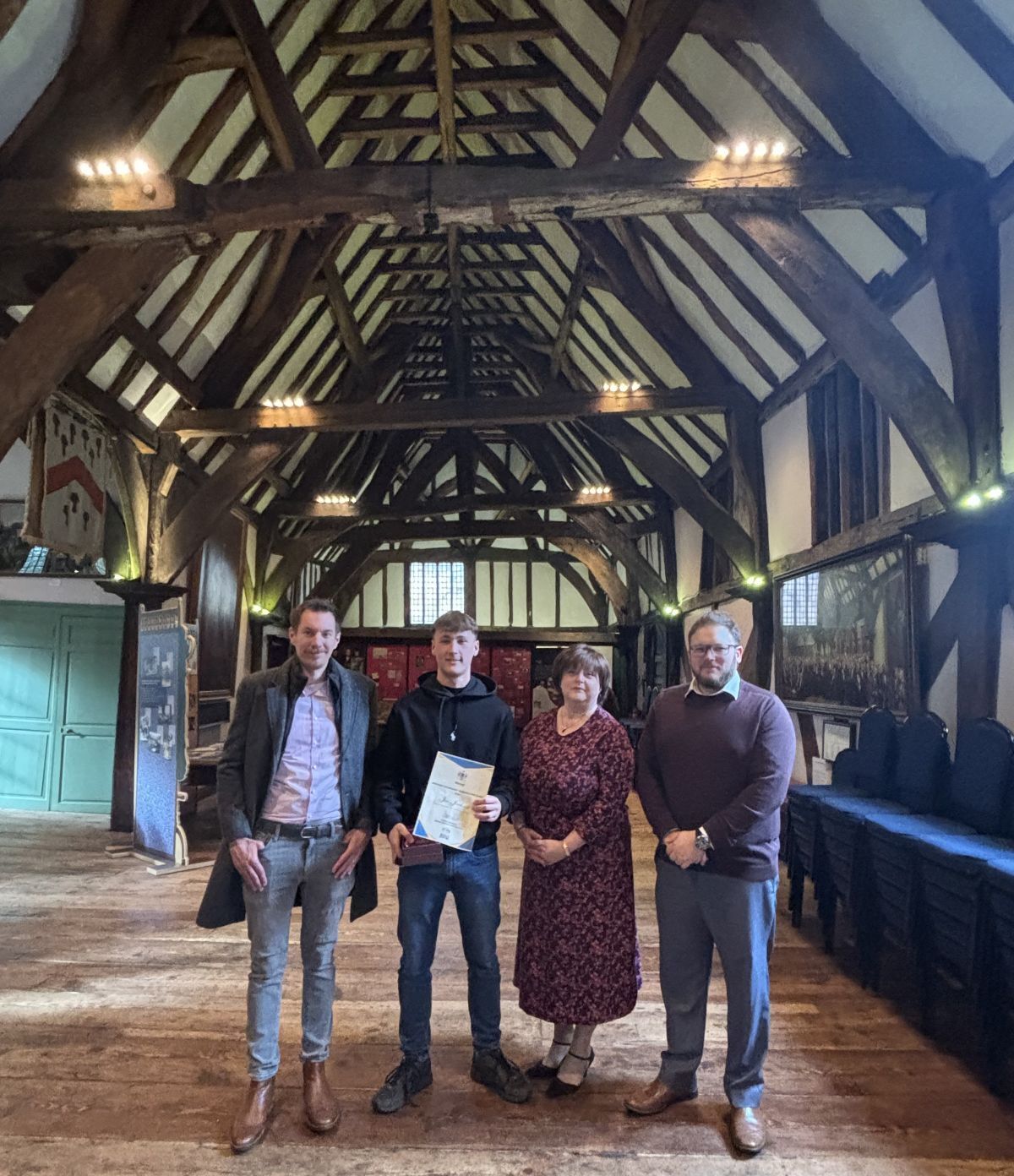 K Core representatives Greg Smith Elaine Hukins and James Selway stand in the Merchant Adventurers Hall with award winner Joe Jackson and his certificate