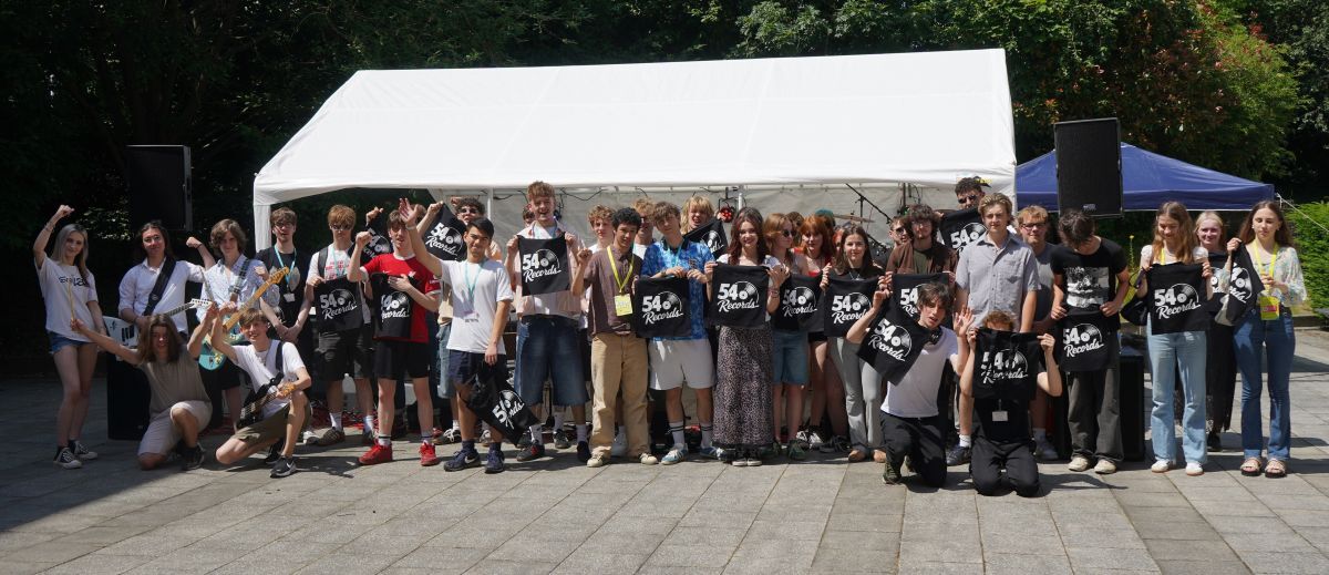 Music students pose with 54 Records tote bags in front of a marquee at York Colleges Welcome Fest celebration
