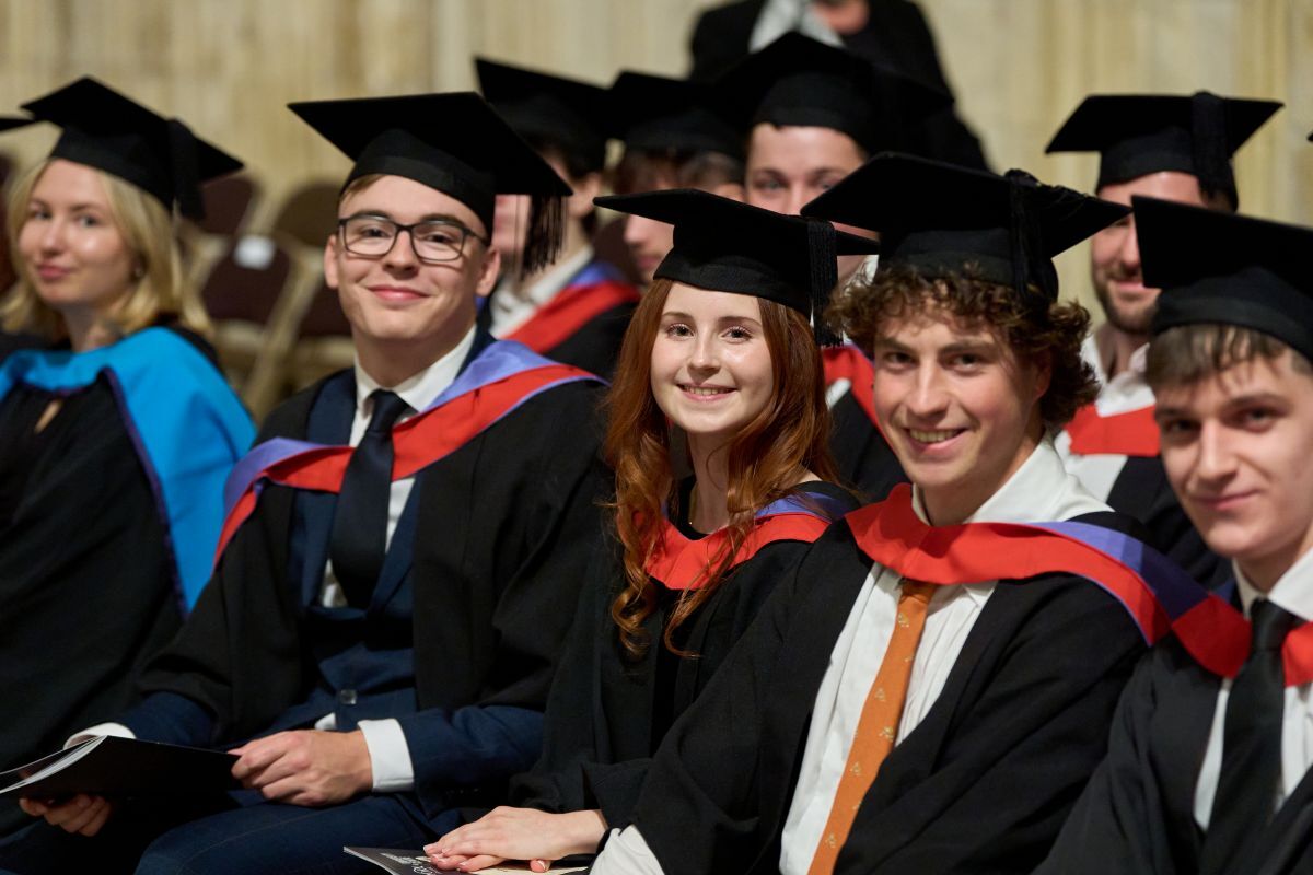 Robyn Bradley smiling at the camera as she sits in York Minster with fellow course garduates