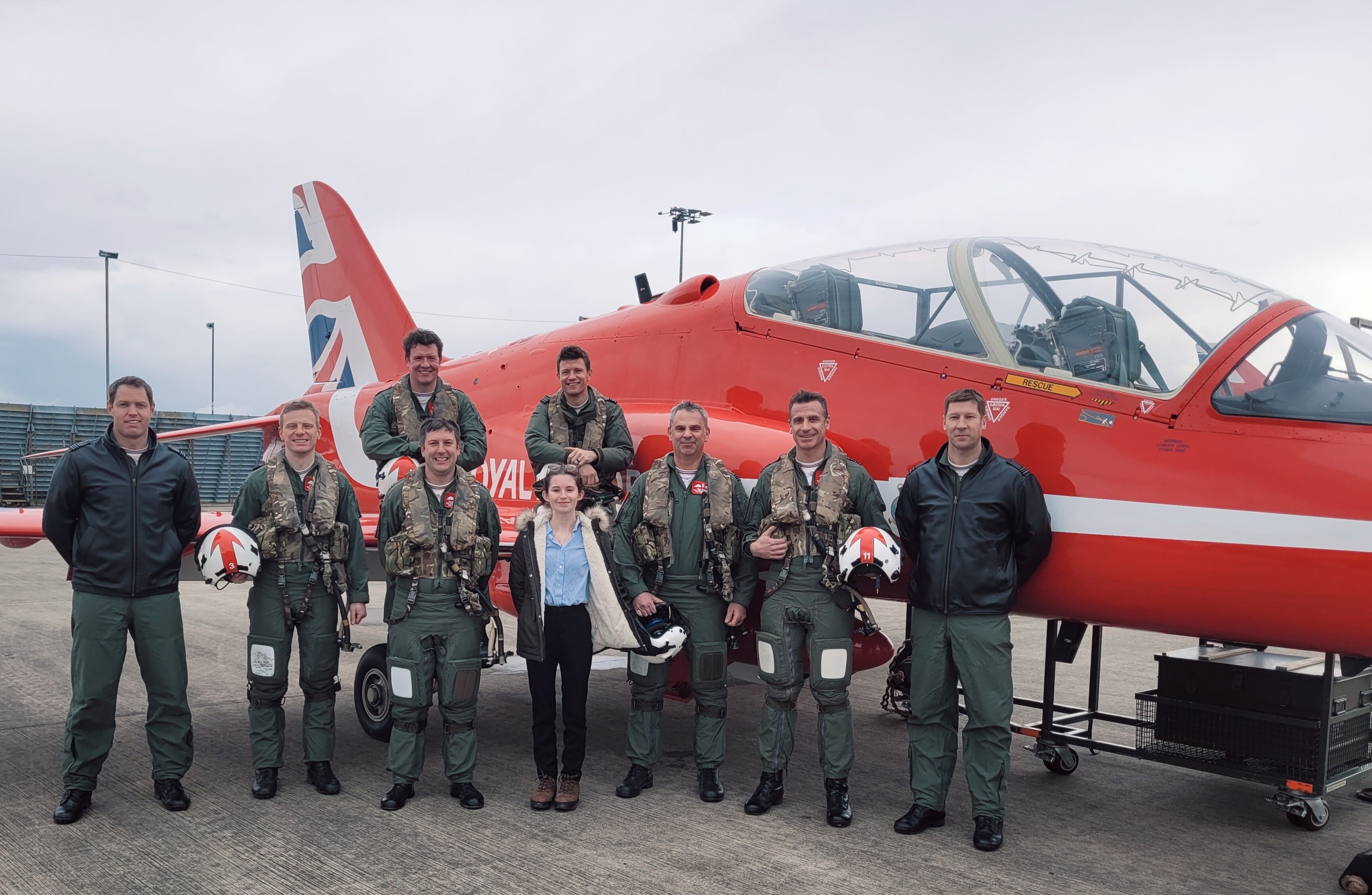 Robyn Bradley stands in front of a Red Arrows plane with a group of pilots and technicians