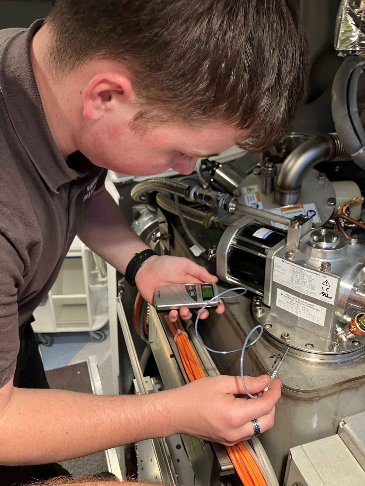 Sam Welch checking a meter reading on a device that is connected to machinery