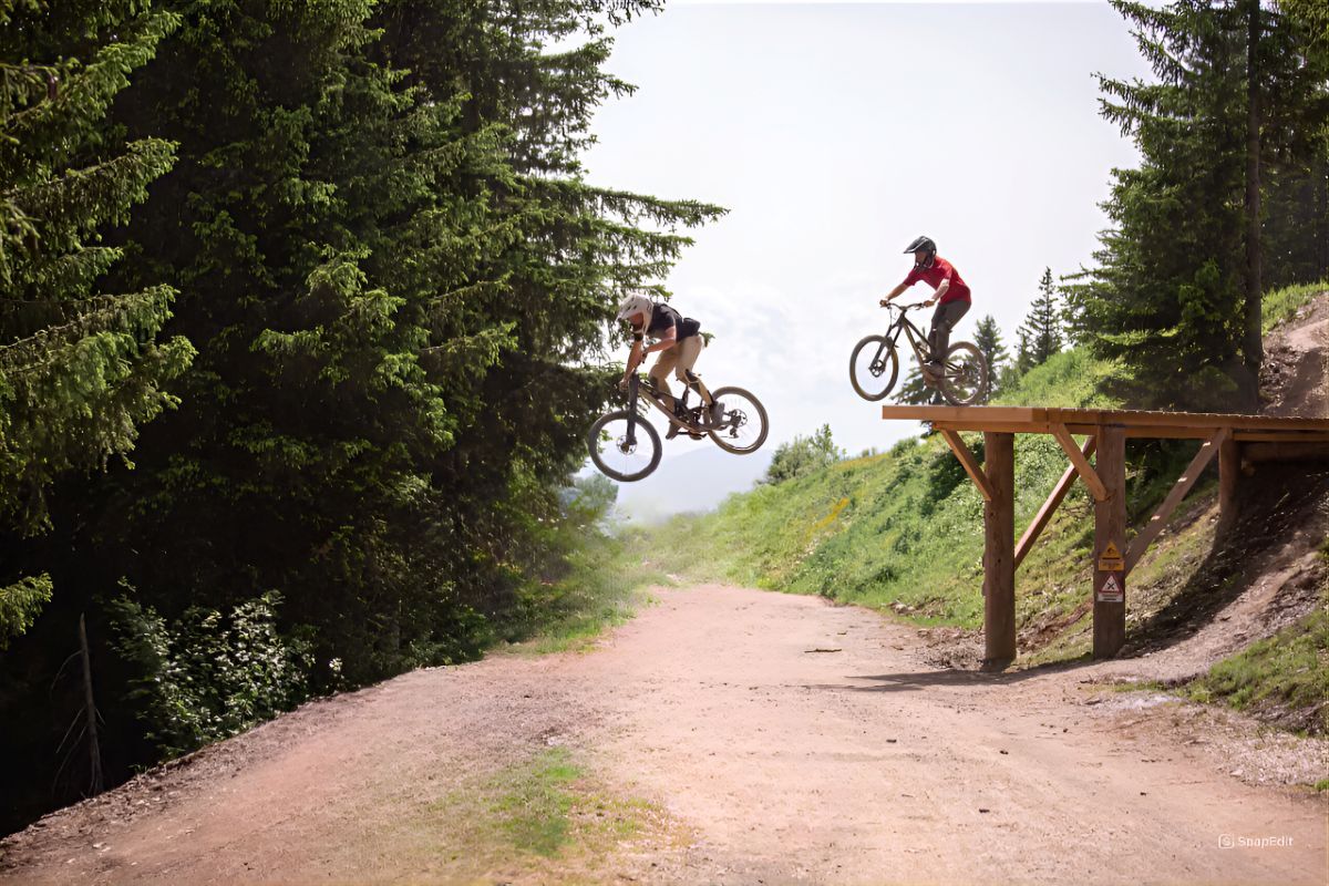 Sam Welch flying through the air on his bike after riding off a wooden ramp in Morzine with trees in background