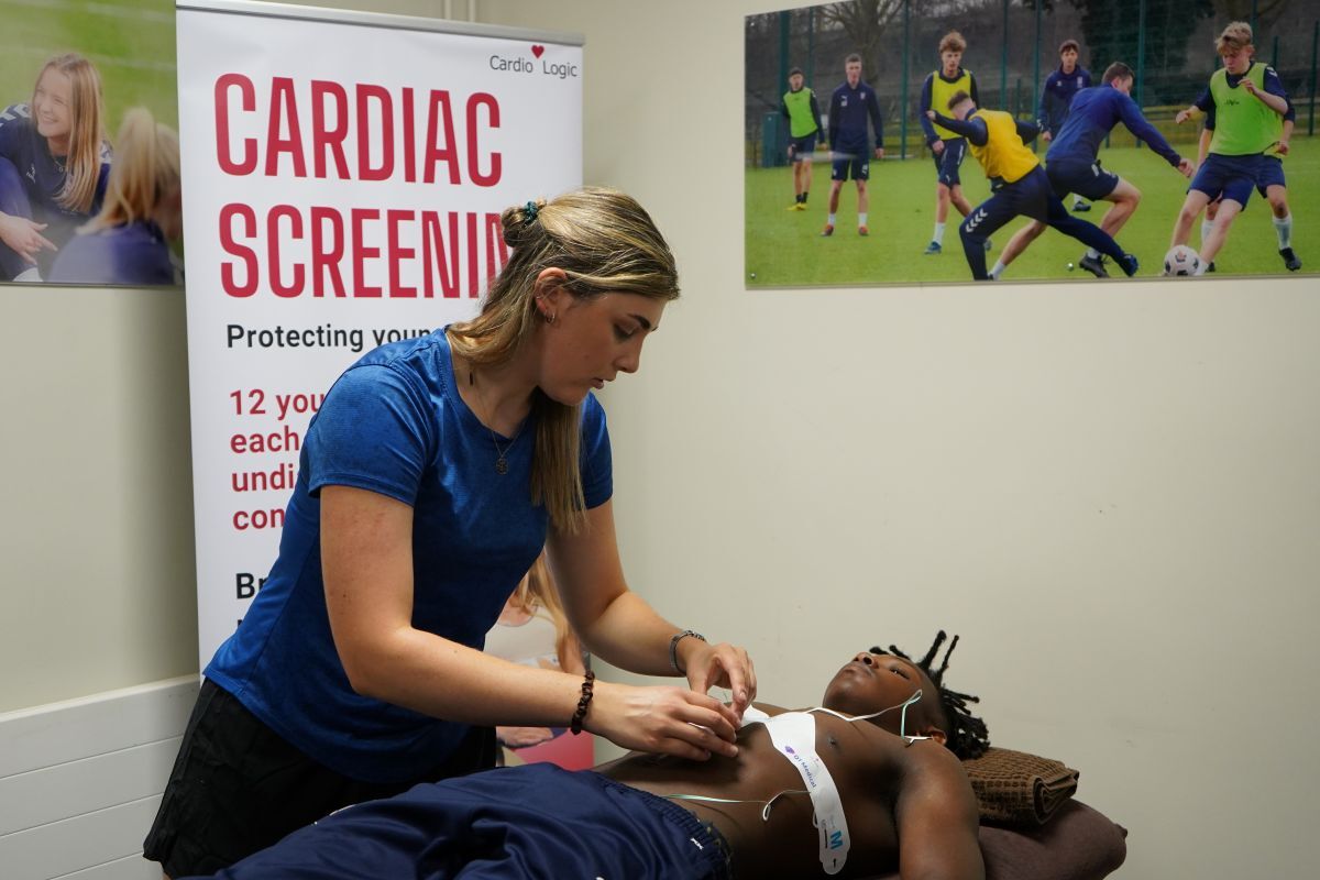 Student Jaden Ncube lays down on patient bed with ECG electrode patches being applied by sports tutor Emma Palmer