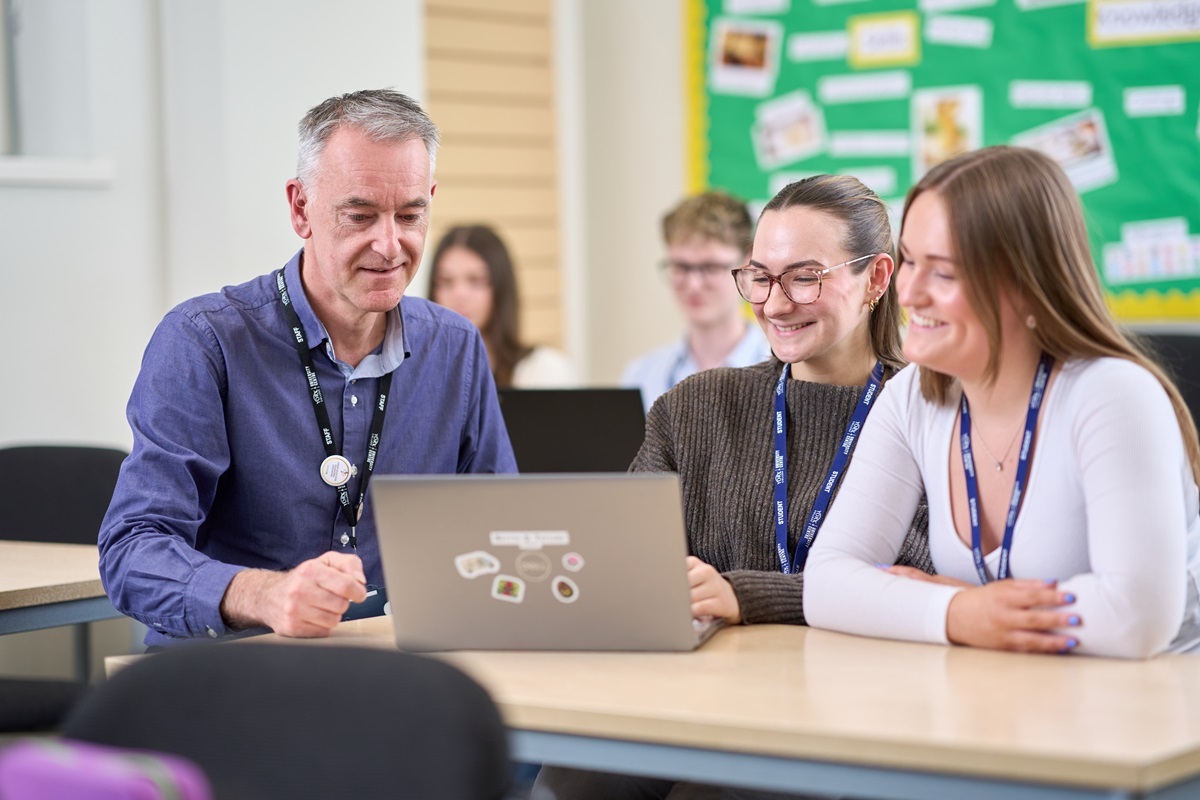 Two students and a tutor look at a laptop CIPD