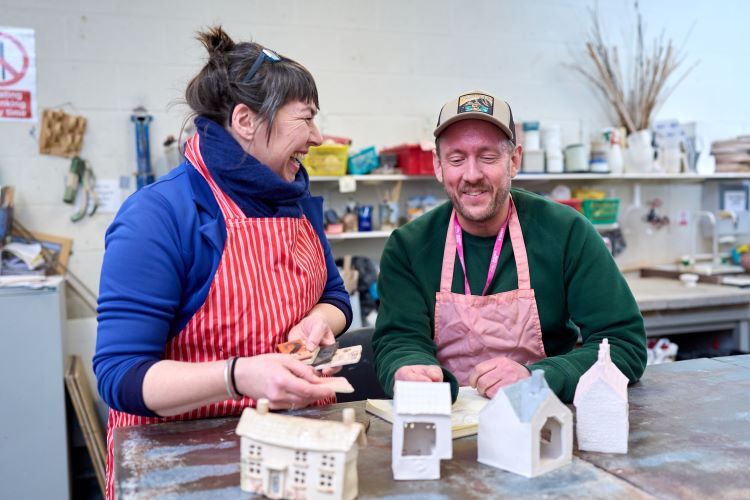 Two students laugh as they work on their pottery