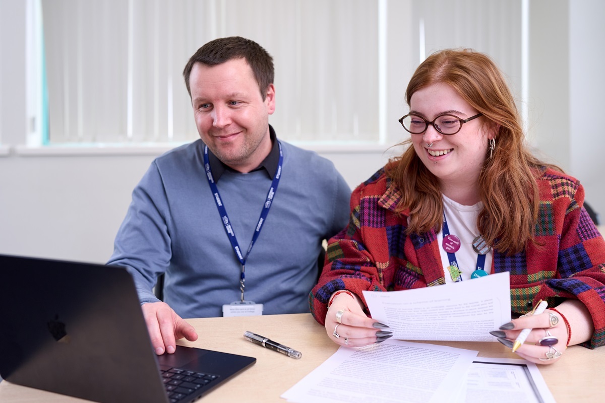 Two students look at a laptop and notes PGCE