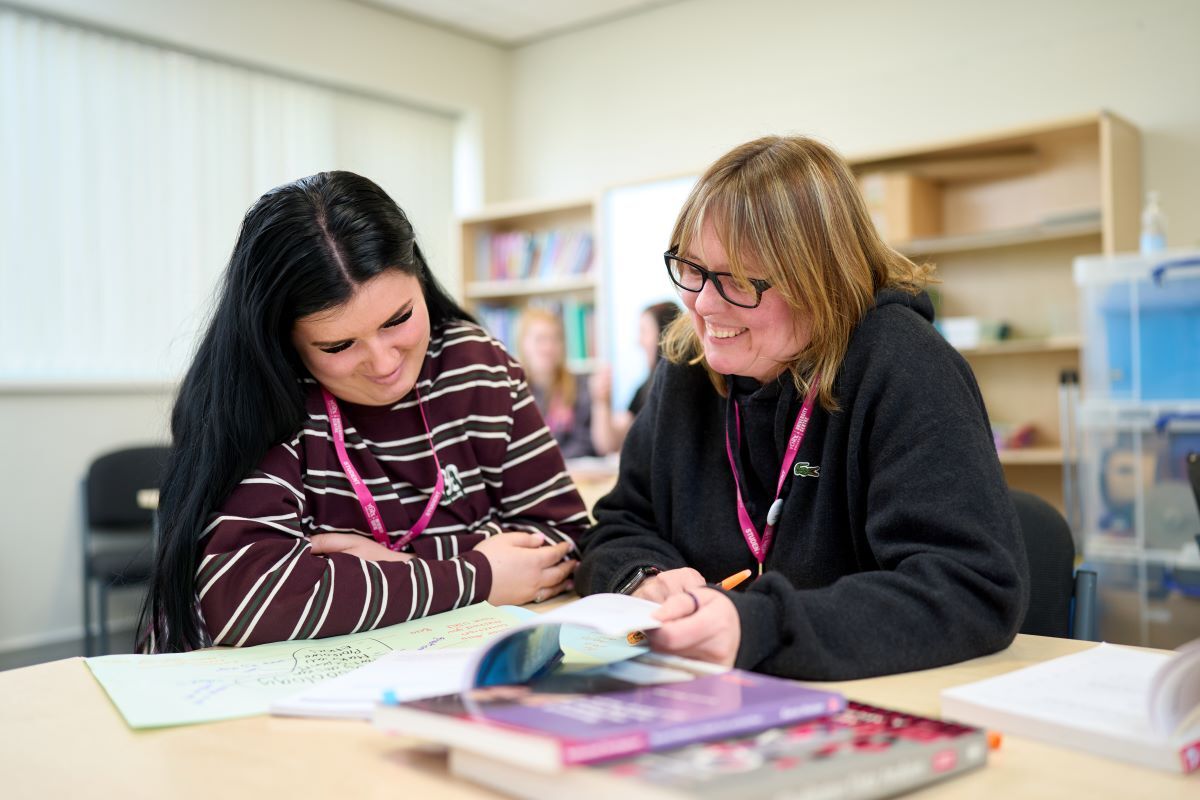 Two students look through a book together Early Years