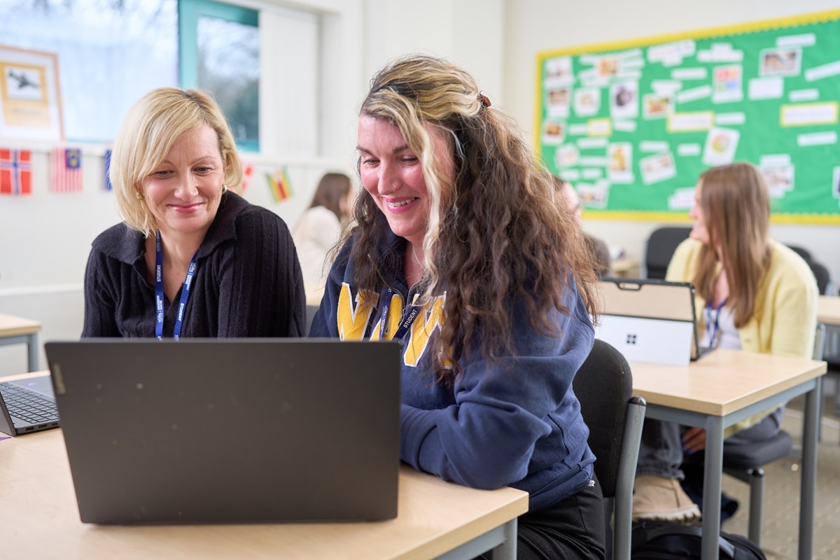 Two students work on a laptop and smile CIPD