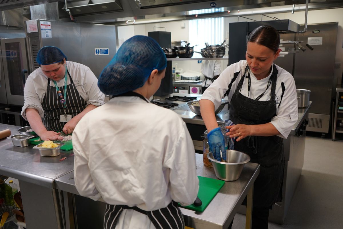 Valentina Zarins assists two students during a service for Fish Chips in York Colleges The Cookery kitchen