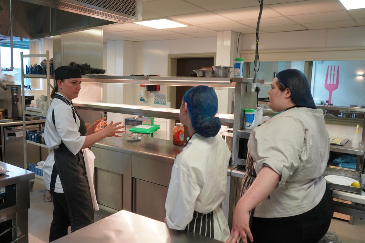Valentina Zarins gives instructions to two students in York Colleges The Cookery kitchen