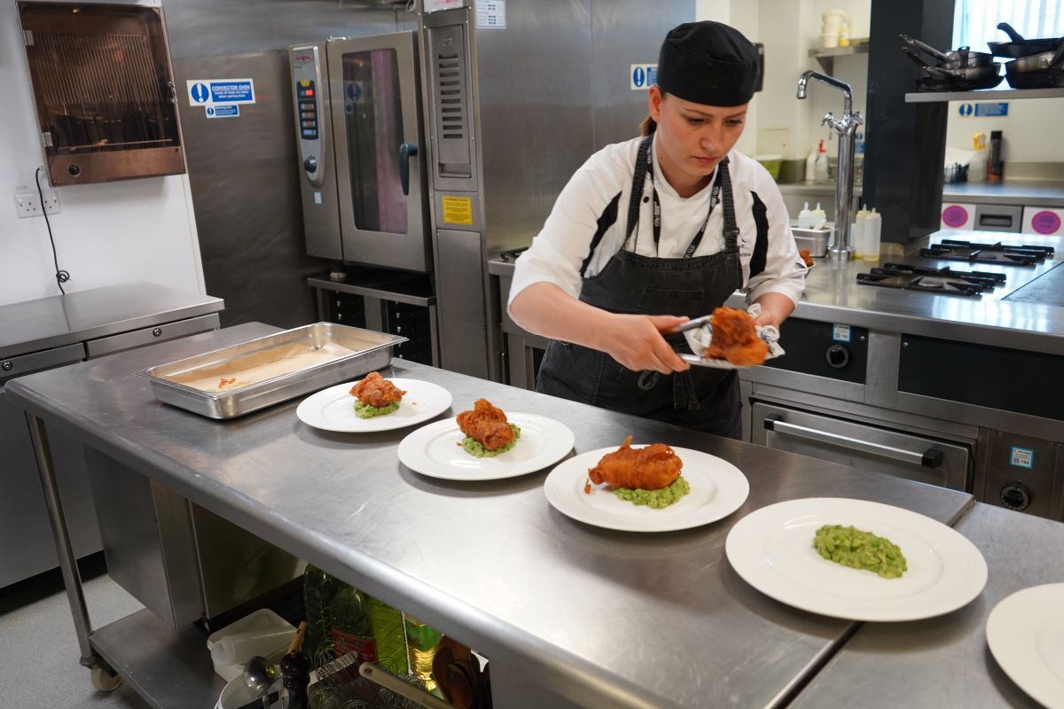 Valentina Zarins plates up battered fish on top of a bed of mushy peas in York Colleges The Cookery kitchen