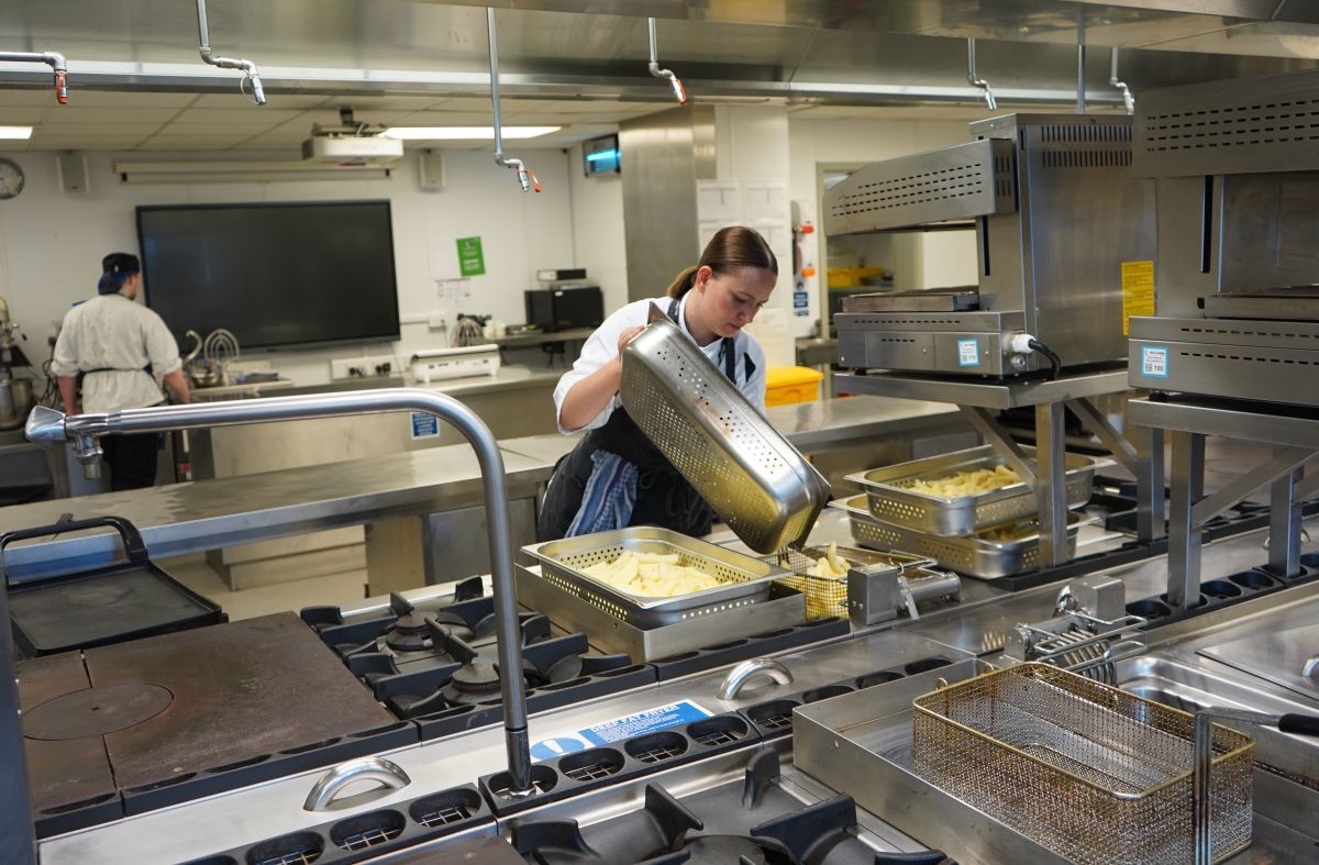 Valentina Zarins tips a tray of chips into the fryer in York Colleges The Cookery kitchen