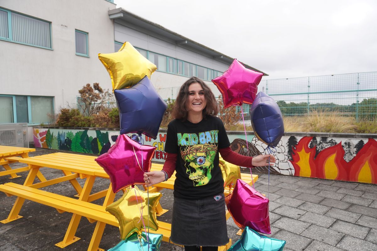 Winnie Parry celebrates her GCSE results holding star shaped balloons in the York College Podium Garden