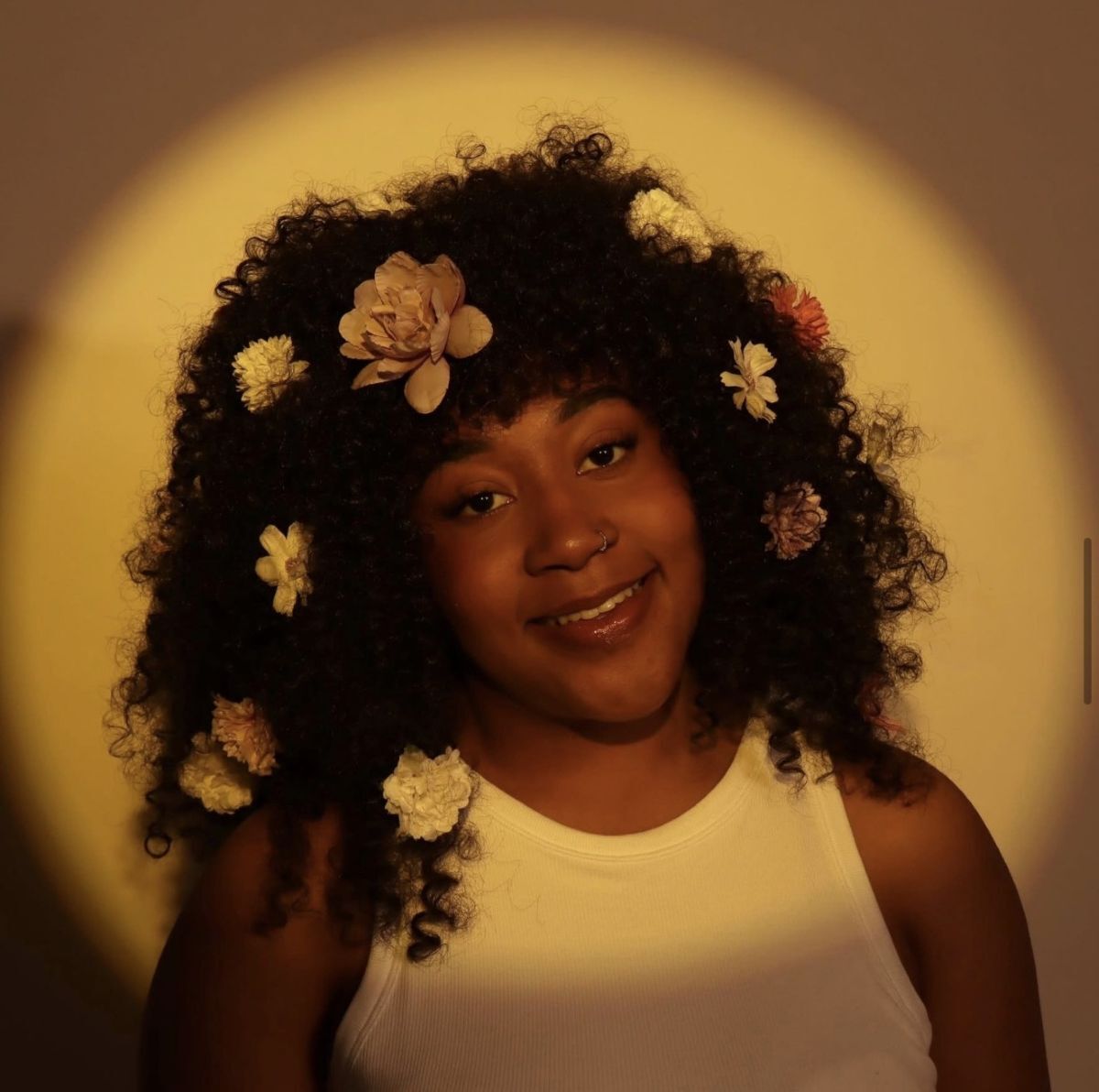 Young woman models afro style wig with rose flowers in it